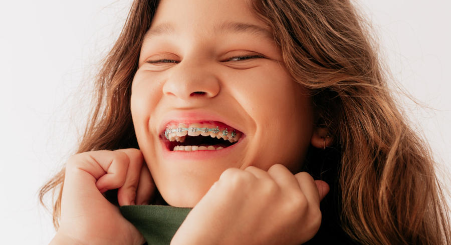 A woman with green braces smiling in a green turtleneck
