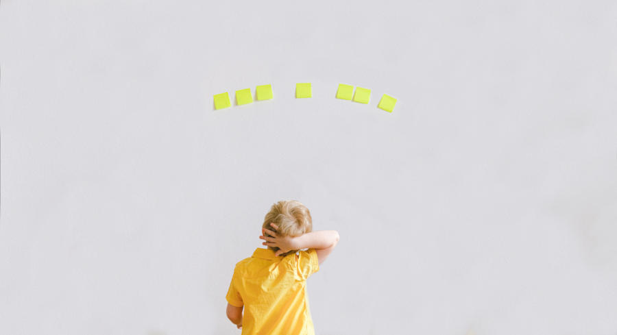 A child looks at a wall full of postit notes trying to decide which one he likes best