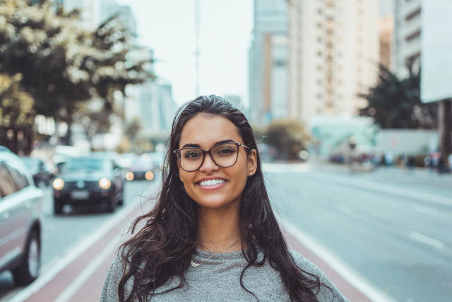 A woman in the city smiling straight at the camera