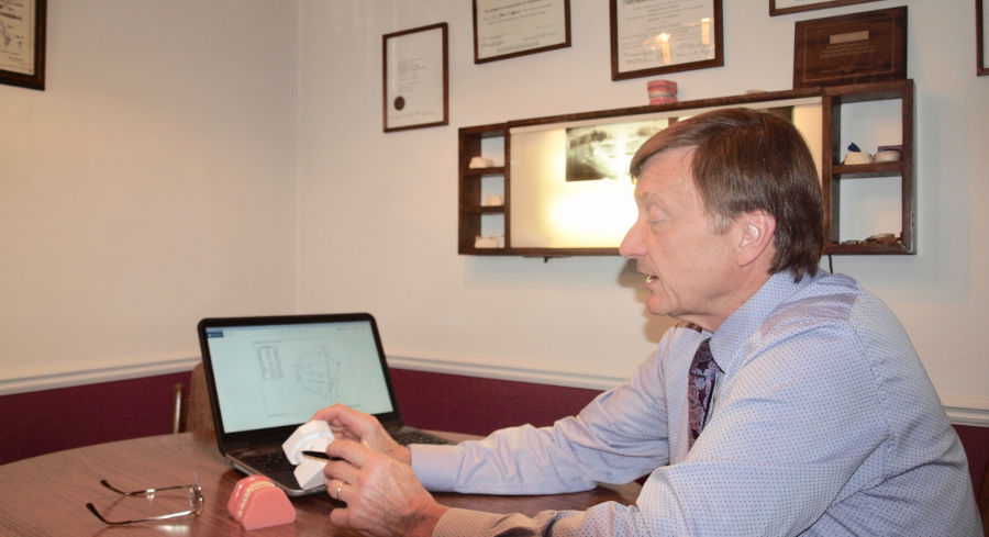 Dr. David Alan Skarin consulting a patient in his office with a dental model and orthodontic software