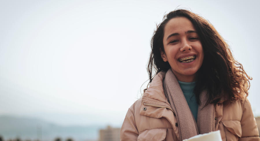 A girl with braces smiling and wearing winter clothes