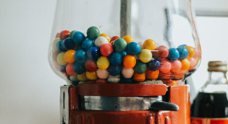 A picture of a boy standing in front of tons of different gumball machines and trying to make a decision on what kind of candy he wants