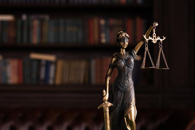 Lady justice standing blindfolded and standing at the ready with her sword