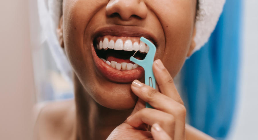 A closeup image of a woman flossing her teeth