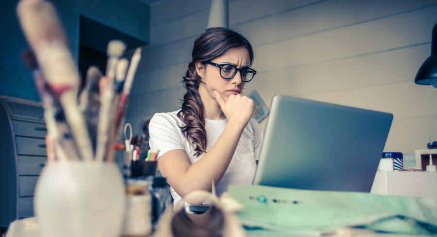 A woman looking at a tv screen furrowing her brow and thinking